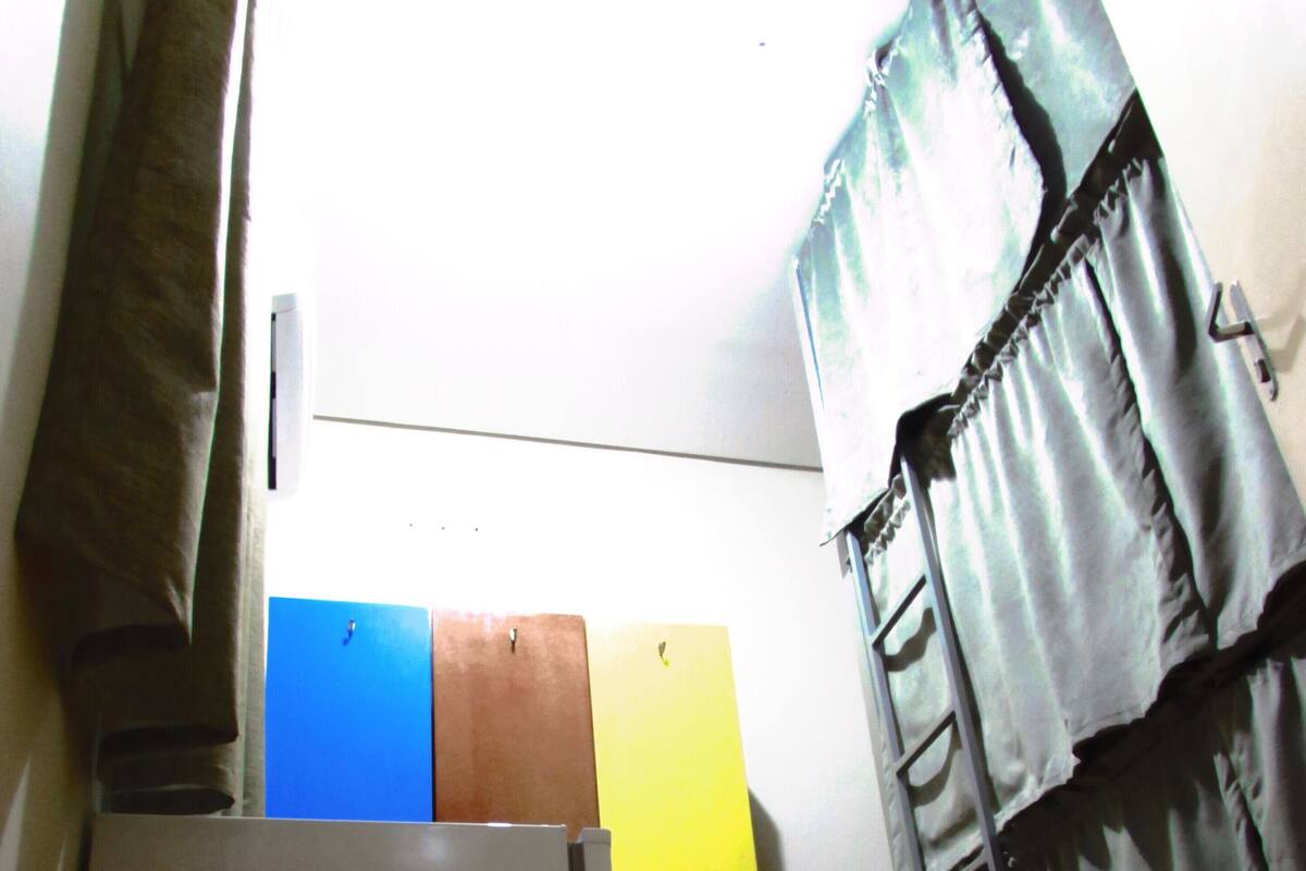Una habitación con piso de madera, una puerta blanca y una escalera metálica apoyada en la pared.