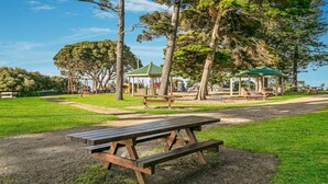 Un espacio para picnic con bancos de madera, mesas y gazebos en un parque.