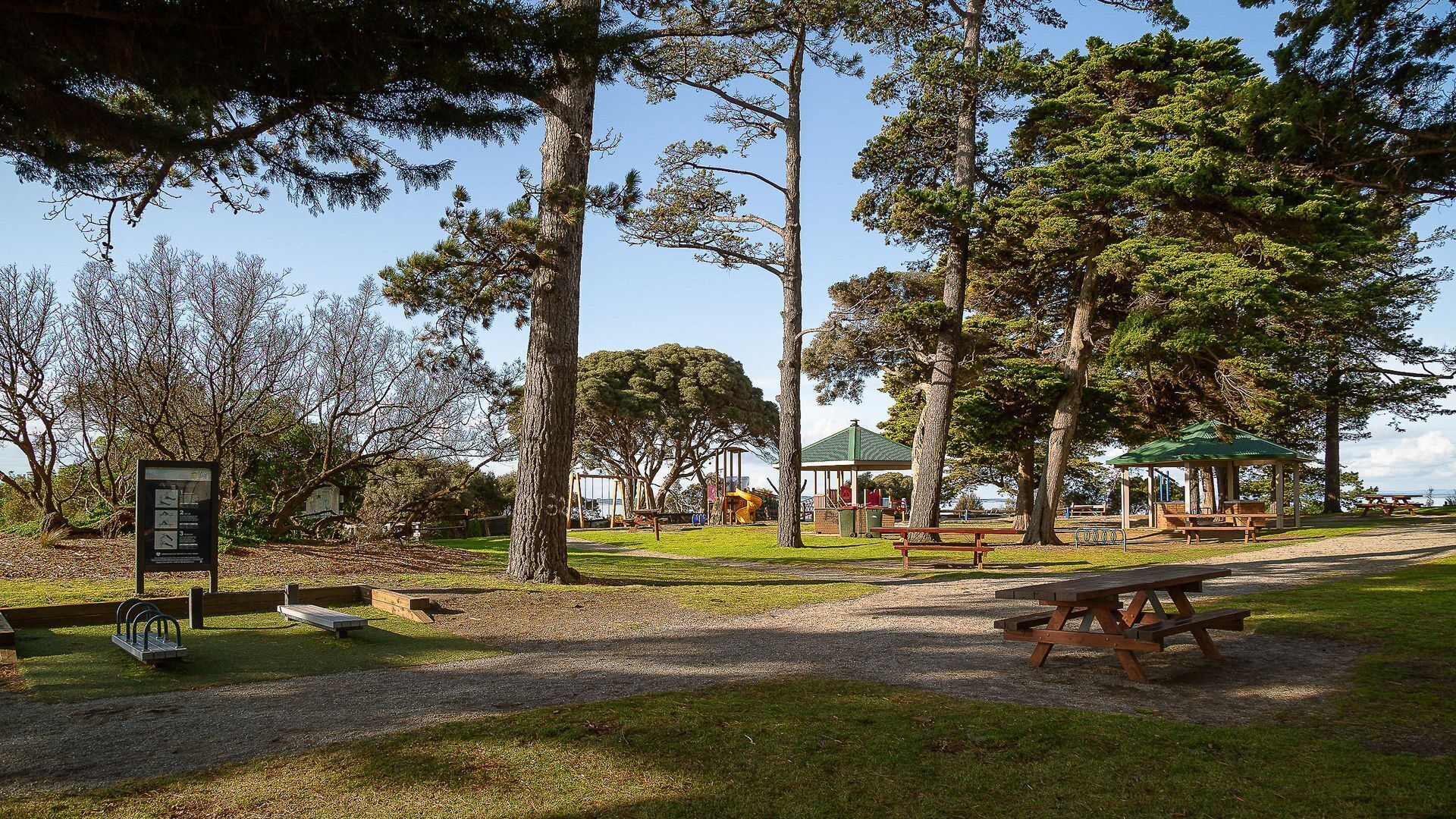 En park med picknickbord, en lusthus och en lekplats.