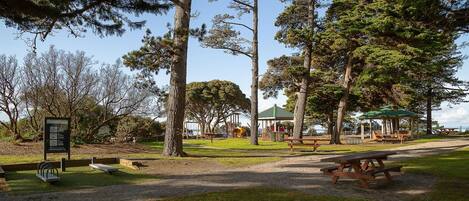En park med picknickbord, en lusthus och en lekplats.