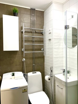 A modern bathroom with a glass shower enclosure, a white toilet, and a sink with a mirror. - City Home Finland Centrum Studio - Sauna (Tampere)