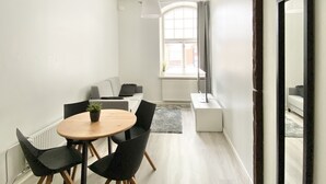 A modern, well-lit room with a round dining table, black chairs, and a large mirror. - City Home Finland Centrum Studio - Sauna (Tampere)