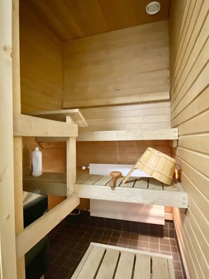 A wooden sauna with a bench and a wooden bucket. - City Home Finland Centrum Studio - Sauna (Tampere)