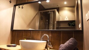 A bathroom with a large mirror, a white sink, and a towel rack. - SUITE ALPAGE (Méolans-Revel)