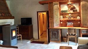 A cozy living room with a fireplace, wooden furniture, and a television. - SUITE ALPAGE (Méolans-Revel)
