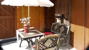 An outdoor seating area with a table, chairs, a white umbrella, and a vase with flowers. - SUMMIT CONTINUATION (Méolans-Revel)
