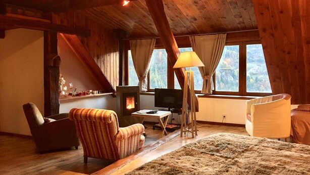 A cozy room with a fireplace, a sofa, a chair, a lamp, and a large window. - SUMMIT CONTINUATION (Méolans-Revel)