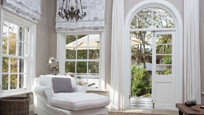 A room with a white sofa, a wicker basket, and a view of the outdoors through large windows. - Romantic hideaway with Mountain Views (Cape Town)
