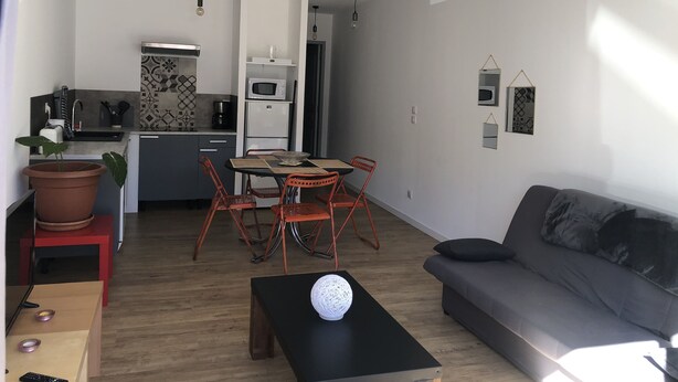 Una sala de estar moderna con un sofá gris, una mesa de centro y un comedor con una mesa y sillas.