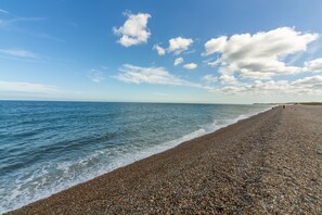 A pebbled beach with a clear sky and calm sea. - Little Emmaus, Cley-next-the-Sea, Norfolk (Cley-next-the-Sea)