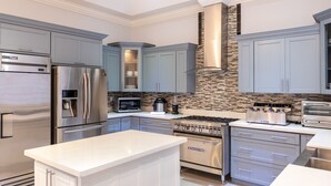 A modern kitchen with stainless steel appliances, grey cabinetry, and a tiled backsplash. - The Sun Seeker Villa Ja 9 Bedrooms . Fully staffed with private chef & butler  (Montego Bay)