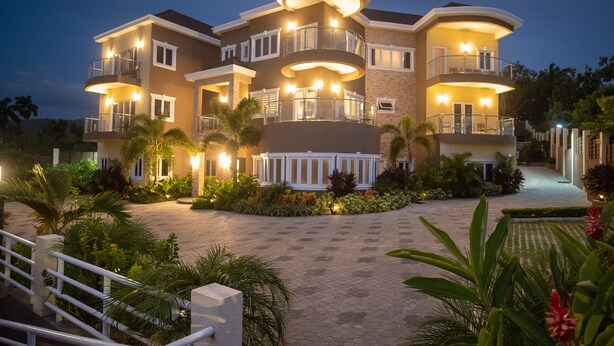 A multi-story house with balconies, a paved driveway, and landscaped gardens. - The Sun Seeker Villa Ja 9 Bedrooms . Fully staffed with private chef & butler  (Montego Bay)