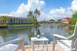 A riverside view with a table set for two, a bottle of wine, and a glass on the table.