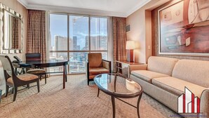 Een hotelkamer met een groot raam, een bank, een glazen tafel en een stoel.