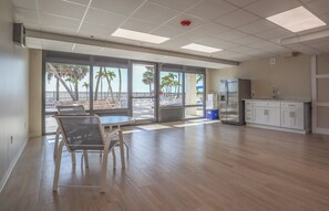 Amplia habitación con ventana grande que da a una zona de piscina, un refrigerador y un lavamanos.