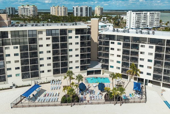 Un hôtel de grande hauteur doté de nombreux balcons, d’un espace piscine central et offrant une vue sur le paysage urbain environnant.