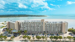 Un hotel de varios pisos con estacionamiento y vista a la playa y el océano.
