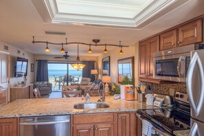 A modern kitchen with a central island, stainless steel appliances, and a view to the outside.