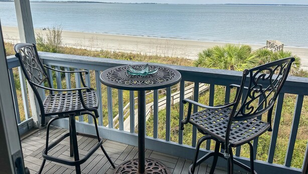 A balcony with two metal chairs and a table, overlooking a beach and the ocean. - Beachfront-Top floor, corner. Waterfront views! Smart TVs and WiFi. Sleeps 2 (Tybee Island)