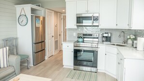 A modern kitchen with white cabinetry, stainless steel appliances, and a built-in oven. - Beachfront-Top floor, corner. Waterfront views! Smart TVs and WiFi. Sleeps 2 (Tybee Island)