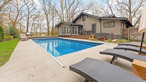 Un jardin avec une piscine, un patio couvert et du mobilier d’extérieur.