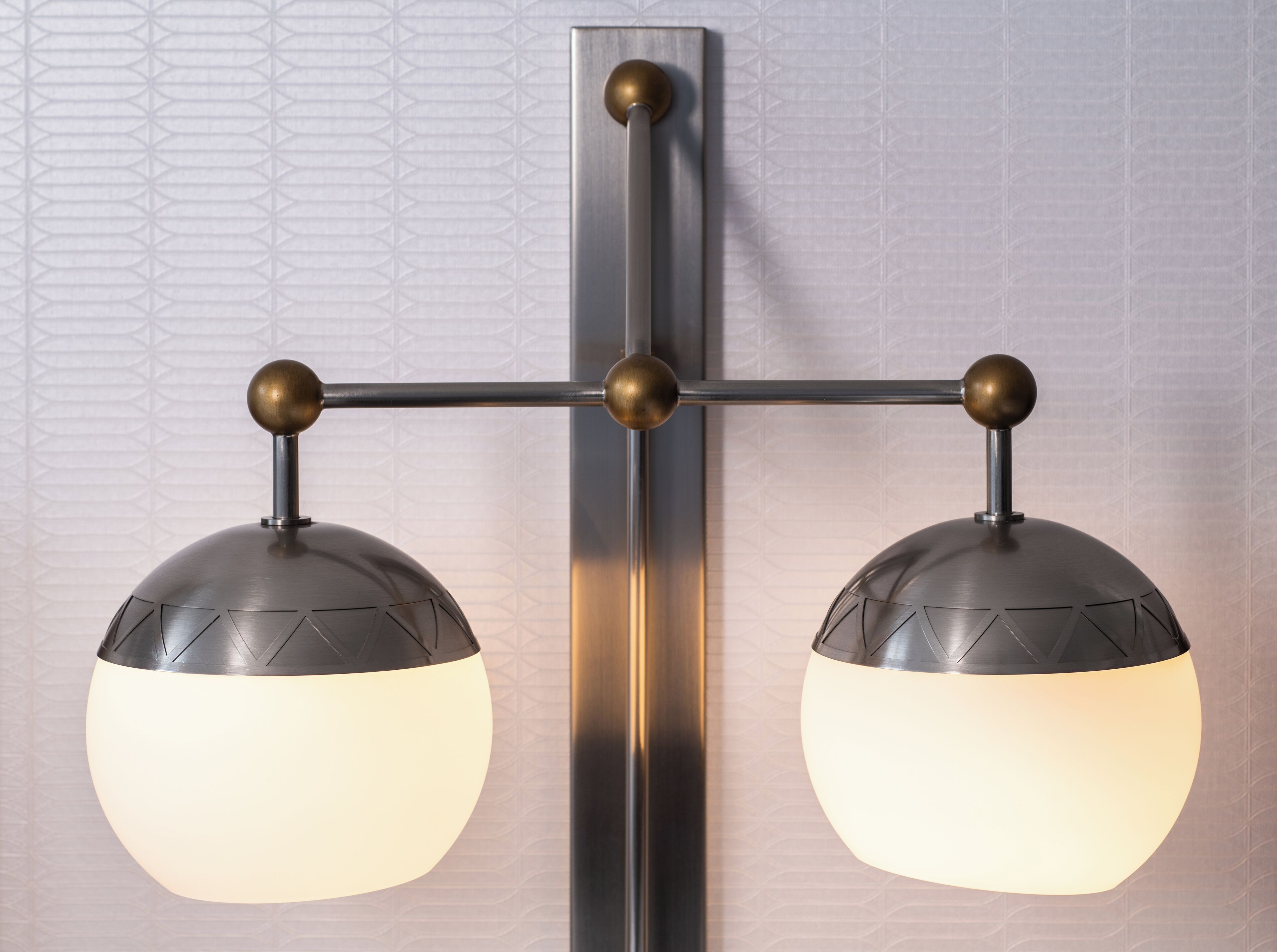 A wall-mounted light fixture with two spherical lamps and a central support structure.