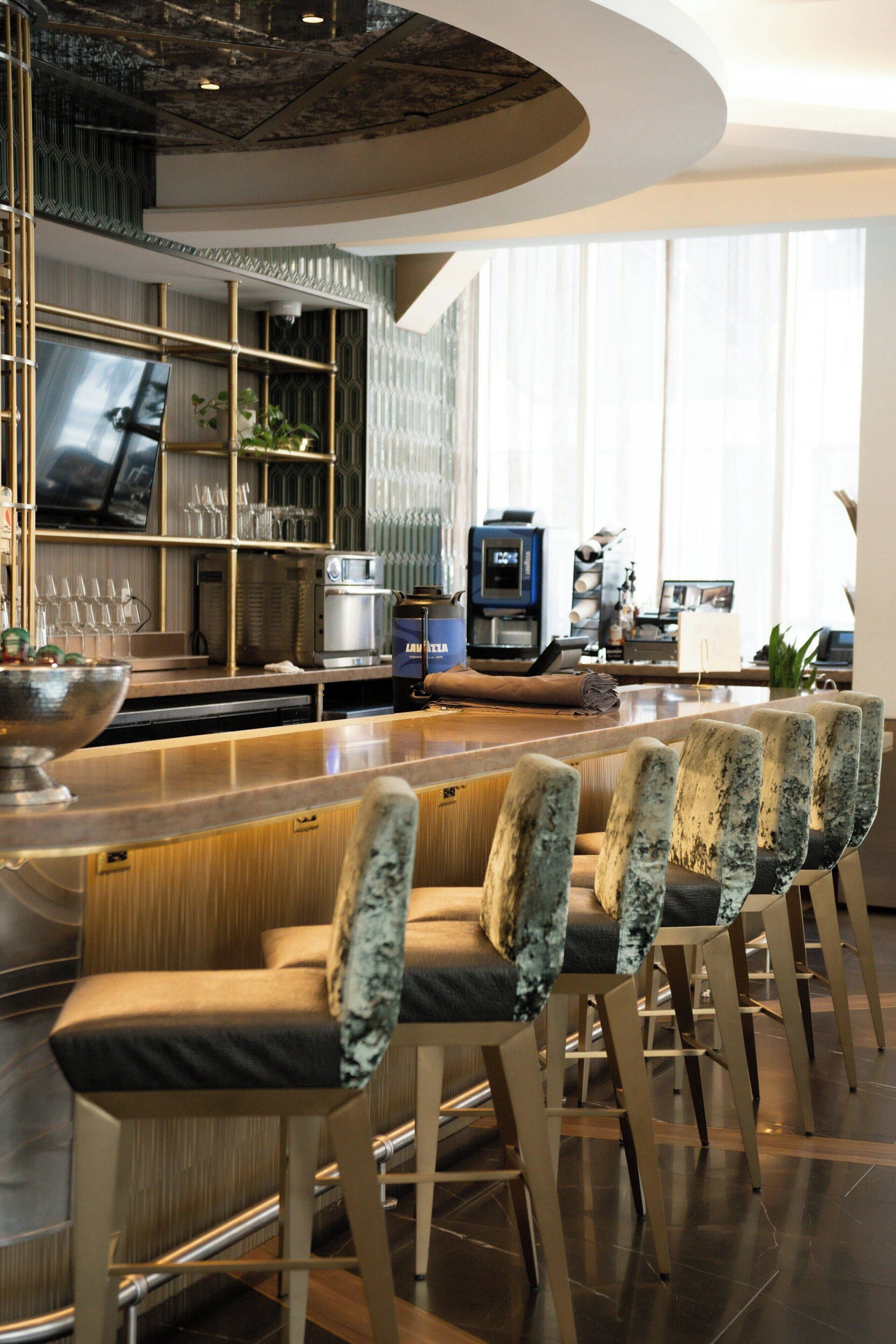 A modern kitchen with a bar area, bar stools, and a coffee machine.