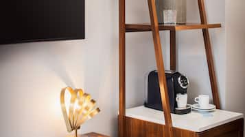 A modern workspace with a wooden desk, a blue chair, a coffee maker, and a ladder shelf.