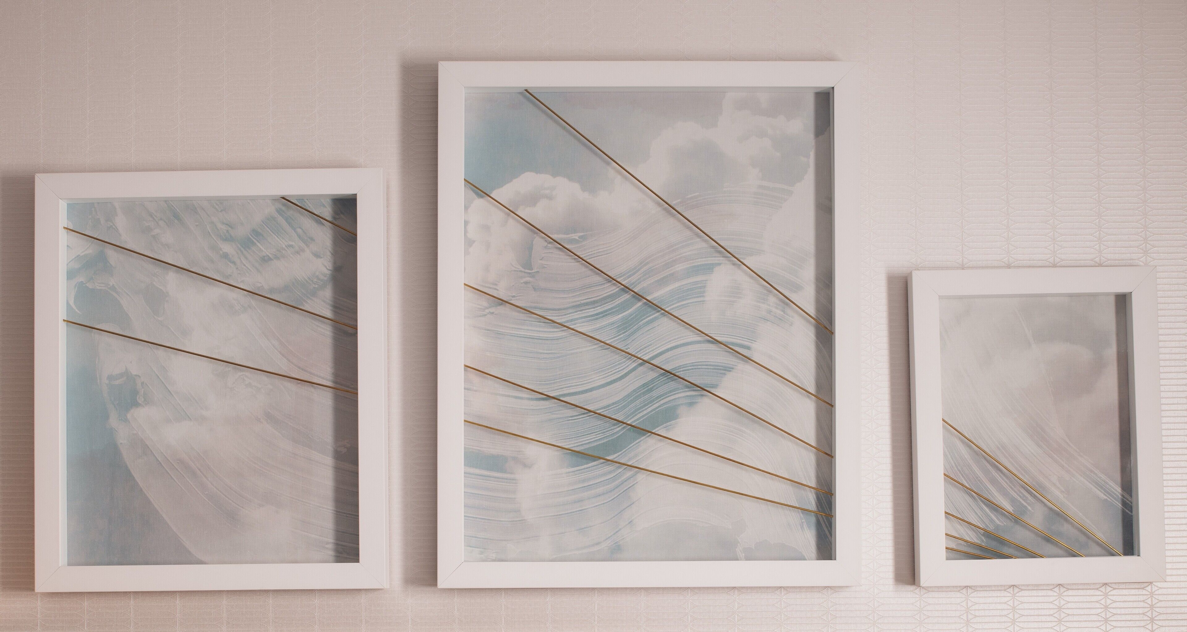 Tres obras de arte enmarcadas con diseños abstractos sobre una pared con textura.