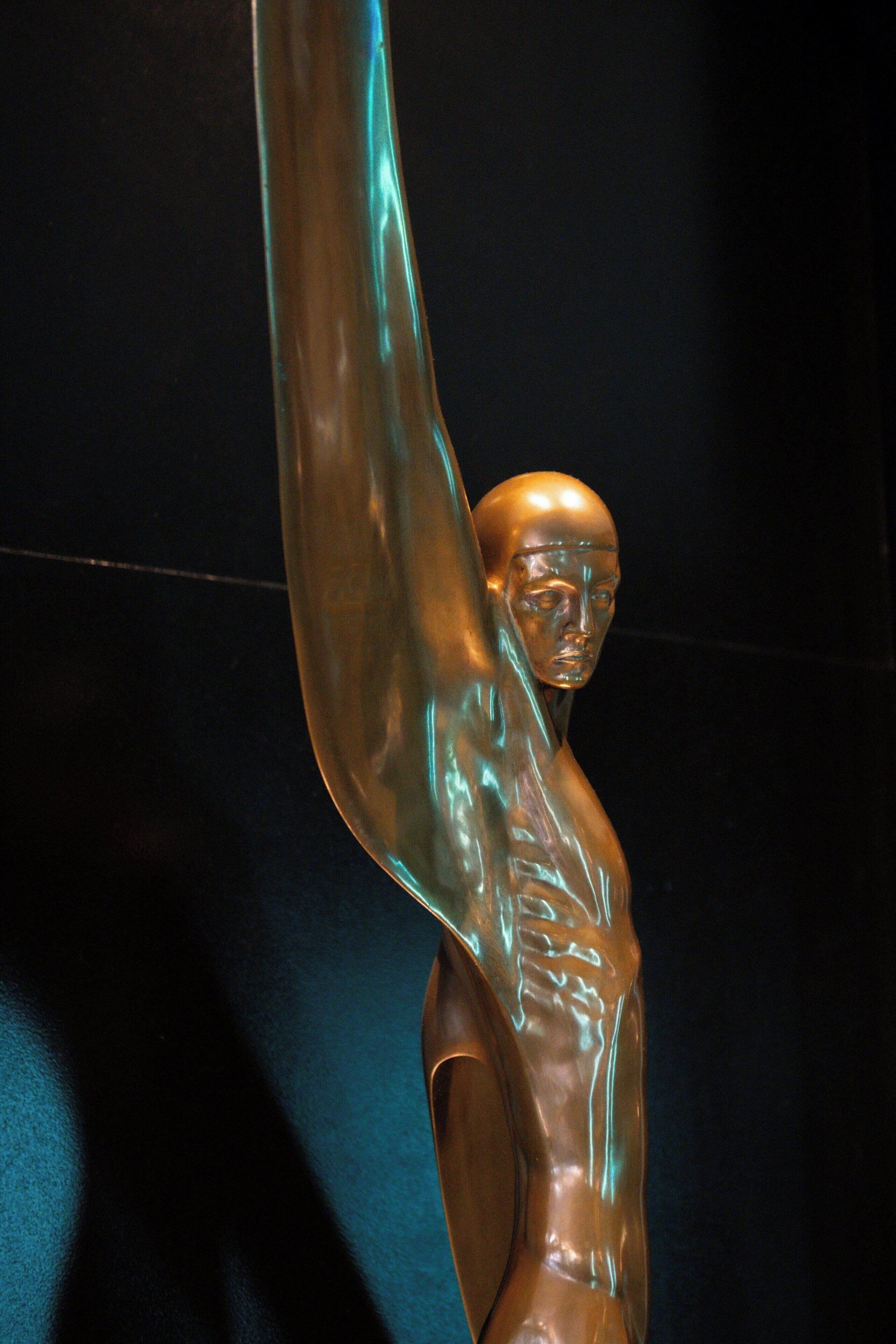 A sculpture of a human figure with one arm raised.
