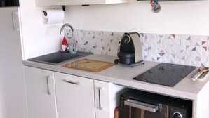 A kitchen with white cabinets, a black countertop, a built-in oven, and a microwave. - Sea views and beautiful pool (Cannes)