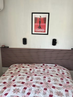 A hotel room with a bed, a framed poster on the wall, and a headboard with horizontal slats. - Sea views and beautiful pool (Cannes)