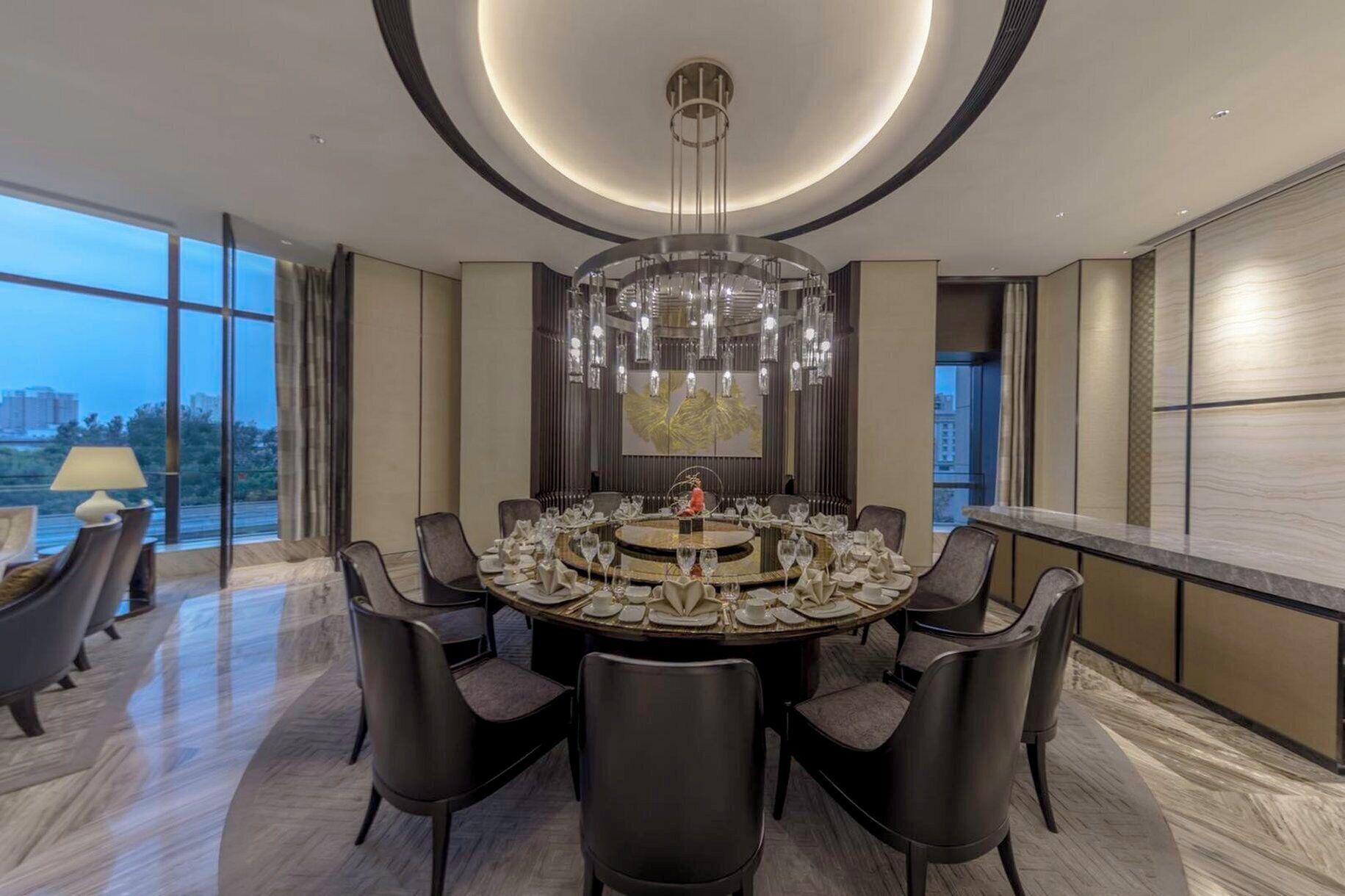 Ein moderner Essbereich mit einem runden Tisch, schwarzen Stühlen und einer großen Chandelier.
