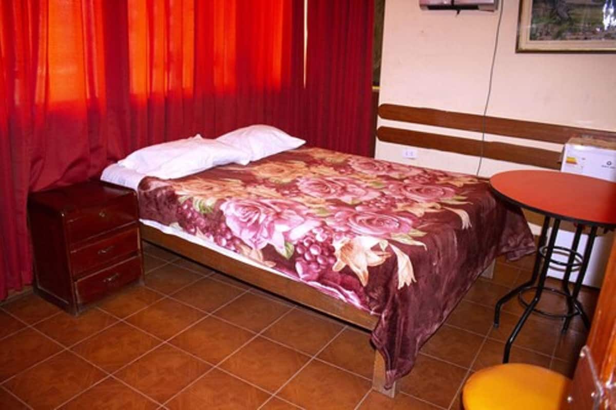 A bedroom with a bed, a dresser, a small table, and a chair.