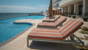 A pool area with lounge chairs and umbrellas, overlooking the sea. - Mazatlán Solaria Oceanview Condo with Pool 704 (Mazatlan)