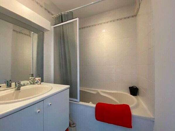 Un baño con lavamanos blanco, espejo y bañera.