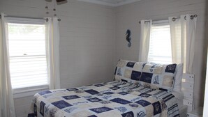 A bedroom with a bed, a nightstand, and a window with curtains. - Beach House with Pool - Pet Friendly (North Myrtle Beach)