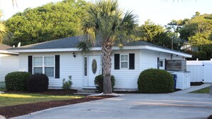 A single-story house with a front porch, a palm tree, and a well-maintained lawn. - Beach House with Pool - Pet Friendly (North Myrtle Beach)