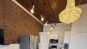 A modern kitchen with stainless steel appliances, a dining area with a round table and chairs, and a brick wall.