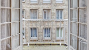 A view through a window with a metal railing, looking out at a building with multiple windows and a stone facade. - Ermine - Intramuros proche plage - St Malo (Saint-Malo)