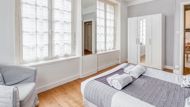 A bedroom with a large bed, a chair, a wardrobe, and a mirror. - Ermine - Intramuros proche plage - St Malo (Saint-Malo)