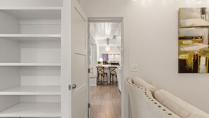 Un pasillo con una puerta blanca que da a una zona de cocina con una mesa y sillas.