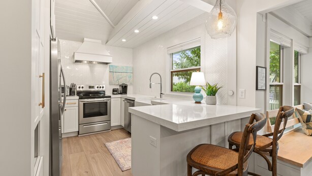 Una cocina moderna con armarios blancos, electrodomésticos de acero inoxidable y una isla grande con asientos.