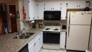 A kitchen with white cabinets, a granite countertop, a microwave, a stove, and a refrigerator. - Beautifully furnished condo at the Villages in McCormick Ranch Scottsdale, AZ (Scottsdale)