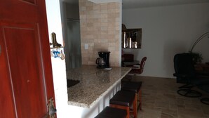 A kitchen with a granite countertop, a coffee maker, and a dining area with a red chair and a black chair. - Beautifully furnished condo at the Villages in McCormick Ranch Scottsdale, AZ (Scottsdale)
