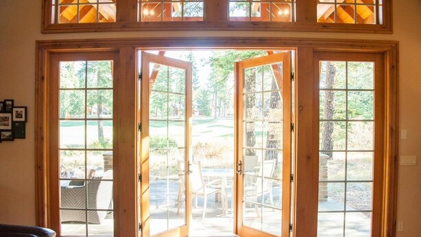 A set of large wooden French doors leading to an outdoor patio area with a stone fireplace and outdoor furniture. - Golf Course View w/ Suncadia Pool Access (Cle Elum)