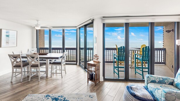 Ein geräumiger Balkon mit Meerblick, eine Essecke mit Tisch und Stühlen sowie eine Sitzecke mit gemustertem Teppich.