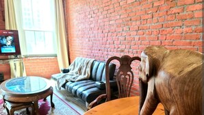 A room with a brick wall, a wooden table, a sofa, and a television.