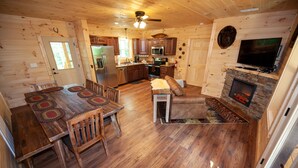 A log cabin interior with a dining area, kitchen, living room, and fireplace. - Quiet Mountain Top Family Cabin- Private, Top Location, VIEWS! (Sevierville)