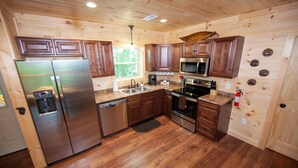 A wooden cabin kitchen with a stainless steel refrigerator, microwave, oven, and dishwasher. - Quiet Mountain Top Family Cabin- Private, Top Location, VIEWS! (Sevierville)